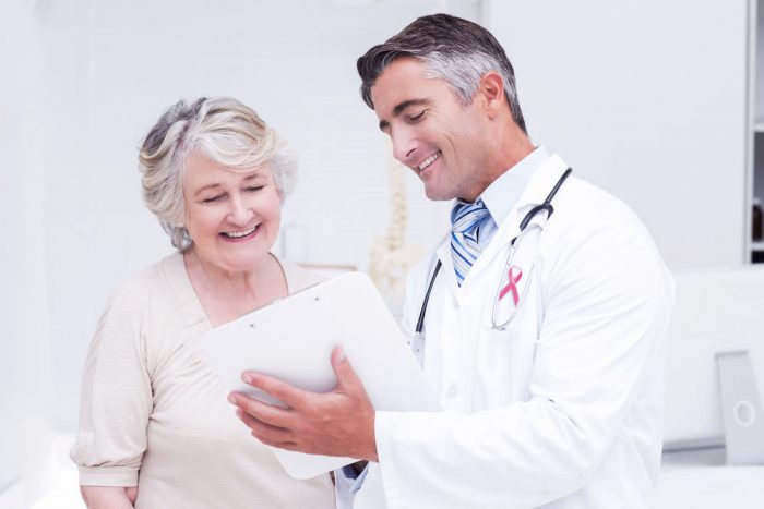 A doctor shows an elderly woman patient good news about her test results.