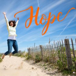 A woman jumps for joy on a beach and the word Hope is in orange in the right hand corner.
