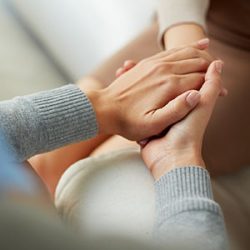 Close-up of two sets of hands clasping one another.
